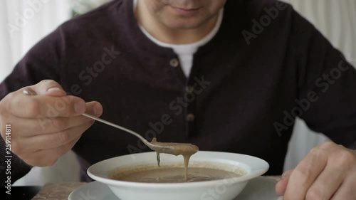 The man at the cafe table is slowly eating soup. Business lunch