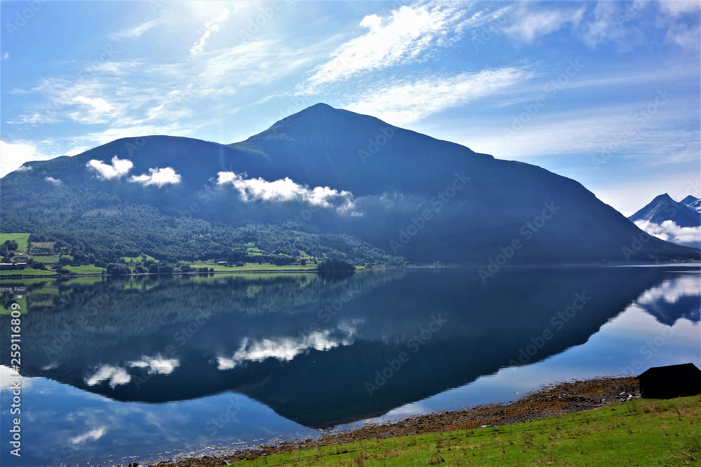 Landscape with a bBlue mountain towerning over still water with a reflection Landscape with a bBlue mountain towerning over still water with a reflection
