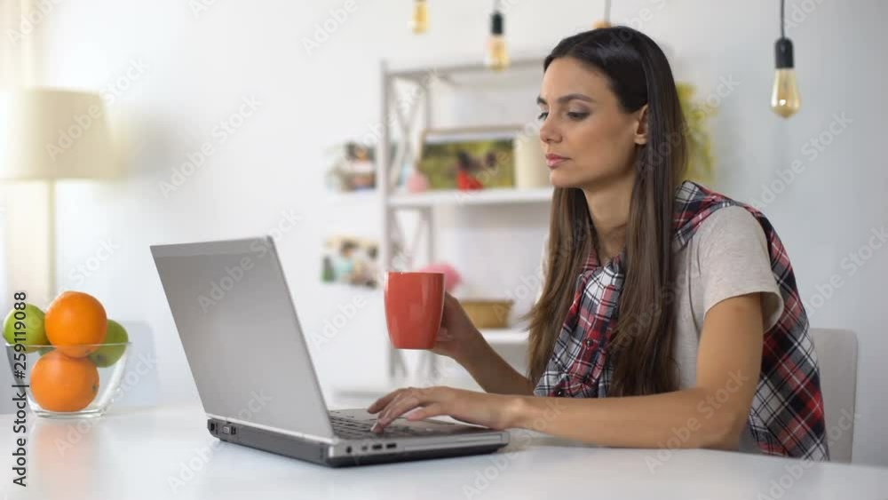 Young female freelancer drinking coffee and working on laptop at home, job Young female freelancer drinking coffee and working on laptop at home, job