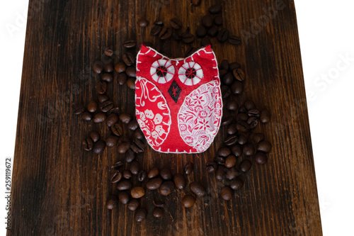 Brown arabica coffee beans with owl on a wooden board.