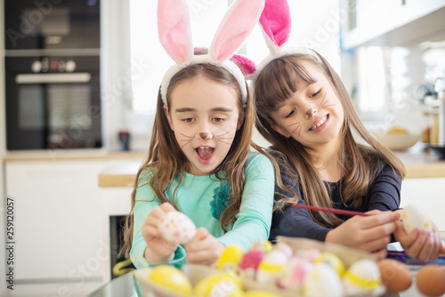 Two cute girls pointing Easter eggs.