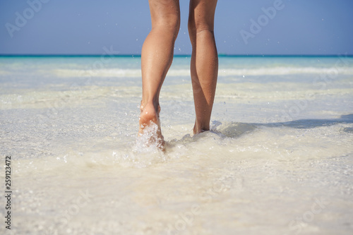 Woman legs walking on the beach sand.
