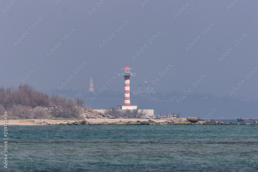 Lighthouse on the Black Sea in Europe. Red and white lighthouse. Lighthouses of Ukraine and Europe. Black Sea Trade Port. Orientation in fog and dark for shipping facilities.