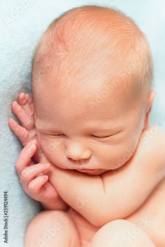 Newborn baby boy sleeping on the light blue background. Portrait close-up