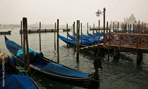 The embankment of Venice with gondolas. Gondola pier on the waterfront. Stop. Empty gondolas are tied to piles and a pier on wooden piles. Venice, Italy, September 4, 2010 © anatol40