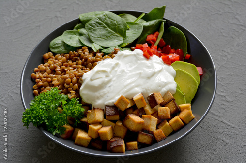 Bowl mit Linsen, Tofu, Spinat, Paprika, Avocado, Joghurt und Petersilie