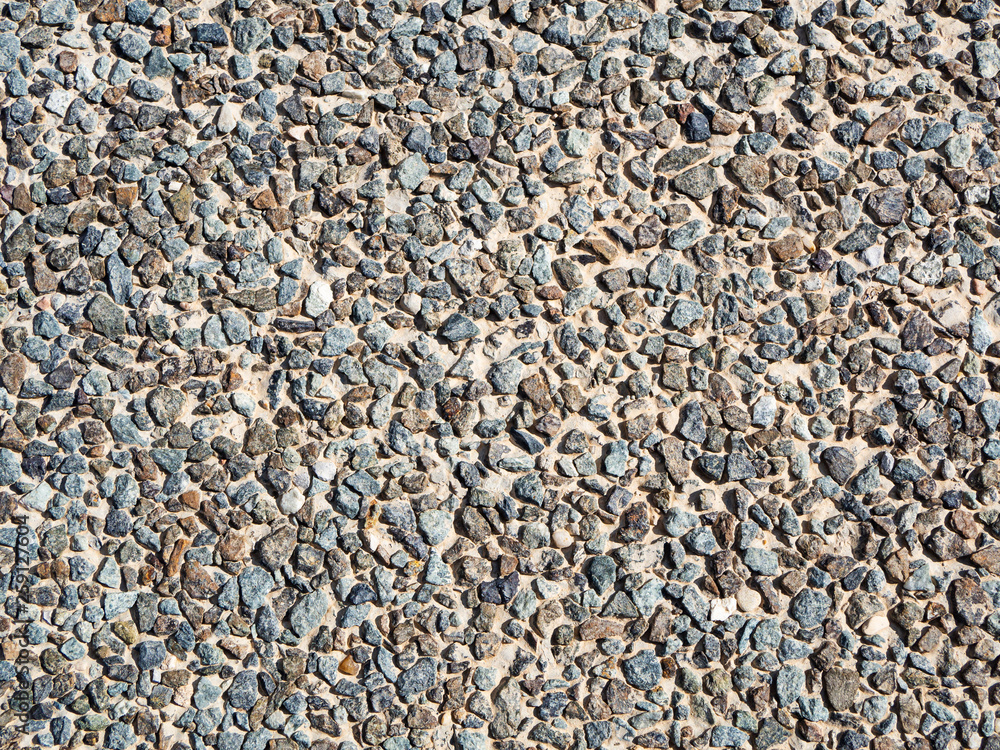 Grunge natural stone background. Various gravel backdrop. Cement wall decorated with stones in sunlight, close up Grunge natural stone background. Various gravel backdrop. Cement wall decorated with stones in sunlight, close up