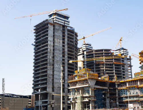 High-rise buildings with yellow cranes and scaffolding at construction site