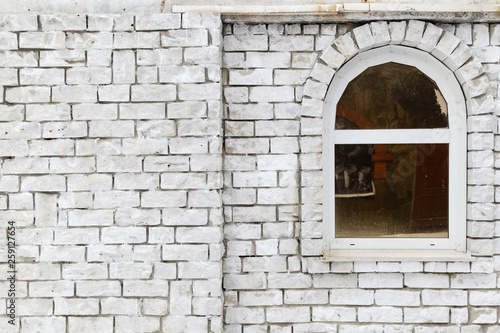 The brick wall painted with white paint with a window