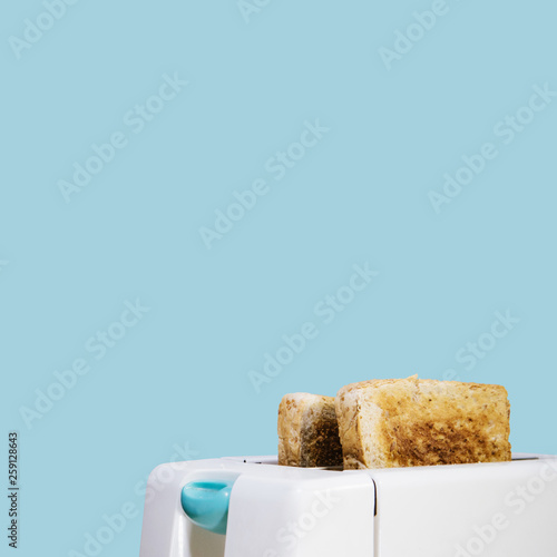 Close-up two sliced whole wheat bread toasted in the white toaster with clipping path and isolated on blue background. breakfast concept.
