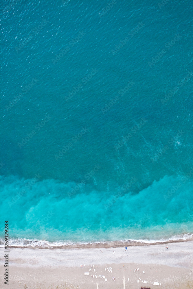 Fototapeta Top-down (Flat lay) view of the beach and the blue (turquoise) sea, sea holidays - bright, vibrant life;