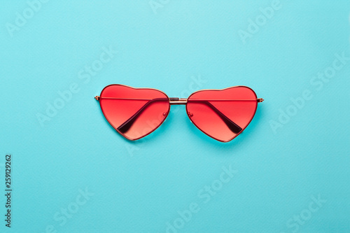 Trend photo on the theme of fashionable orange hue this season. Bright orange heart-shaped glasses on a turquoise paper background.