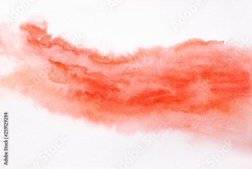 Trend photo on the theme of fashionable orange hue this season. Bright blurred smear of watercolor paint on a white paper background.