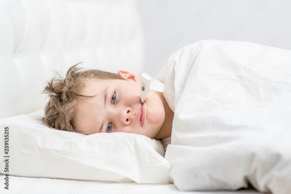 Sick boy under blanket with thermometer in his mouth Sick boy under blanket with thermometer in his mouth