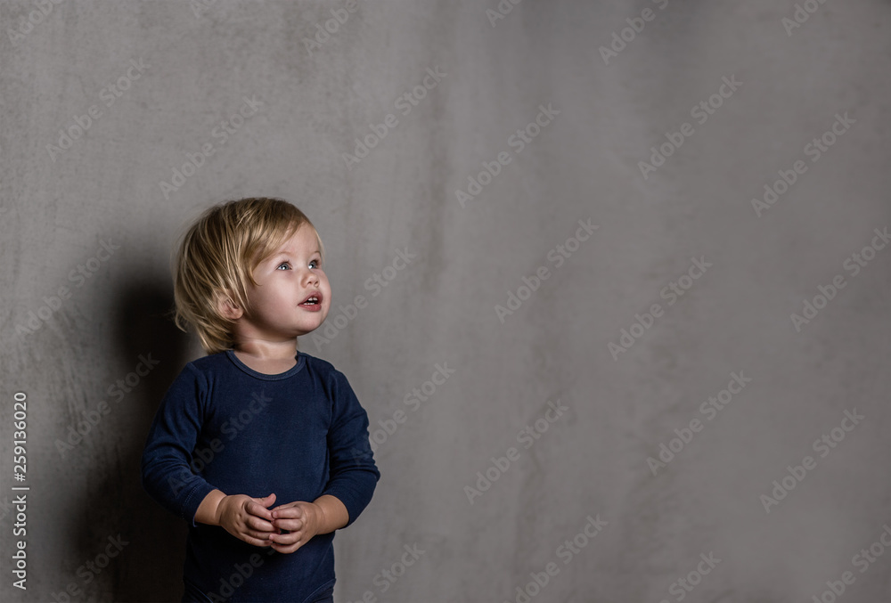 Baby girl on dark background looking up. Empty space for text Baby girl on dark background looking up. Empty space for text