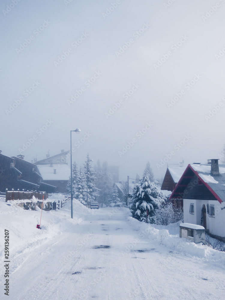 Route enneigée d'un village sous la brume dans les Alpes françaises