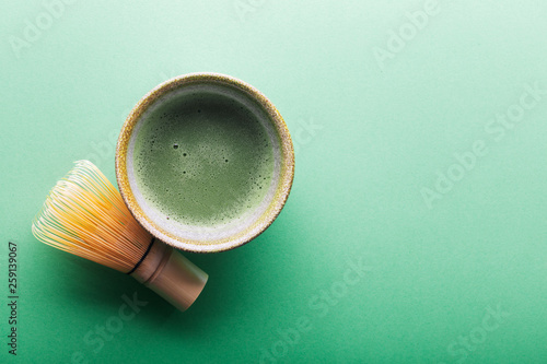 Top view of tea matcha in a bowl and chasen on greeen surface photo