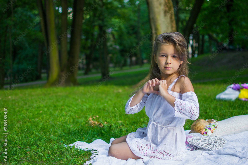 Beautiful little girl in a park on a picnic with straw basket and hat. Spring sunny concept. Happy mothers day. Beautiful little girl in a park on a picnic with straw basket and hat. Spring sunny concept. Happy mothers day.
