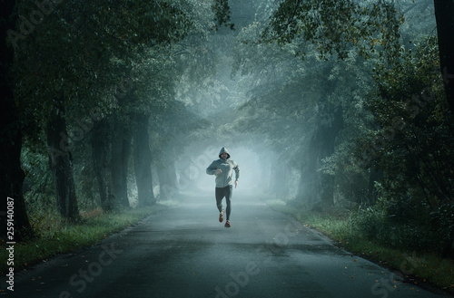 Man running on an empty road on the foggy morning with copy space