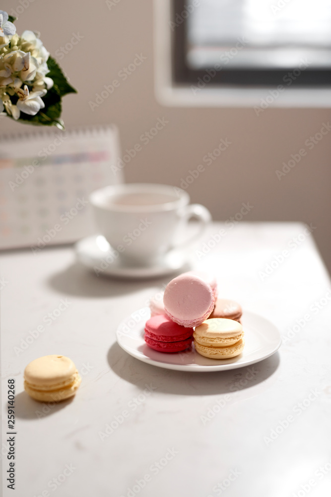 Office table desk. Feminine desk workspace frame with calendar, diary, hortensia bouquet, macaron and coffee on white background. ideas, notes or plan writing concept Office table desk. Feminine desk workspace frame with calendar, diary, hortensia bouquet, macaron and coffee on white background. ideas, notes or plan writing concept