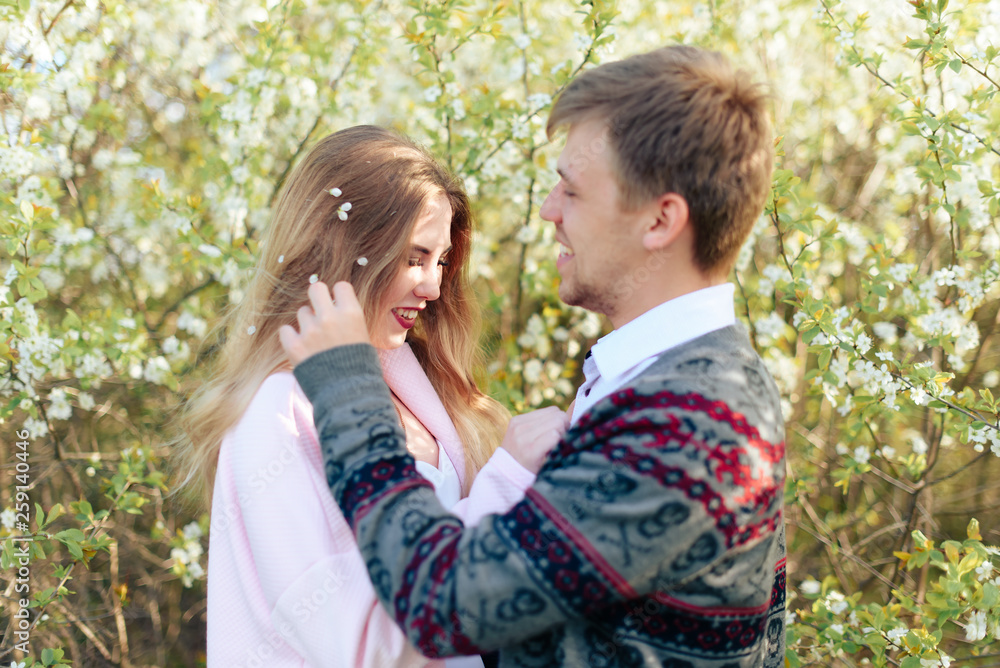 a young couple in love cuddles against the background of blooming spring cherry orchards 1 a young couple in love cuddles against the background of blooming spring cherry orchards 1