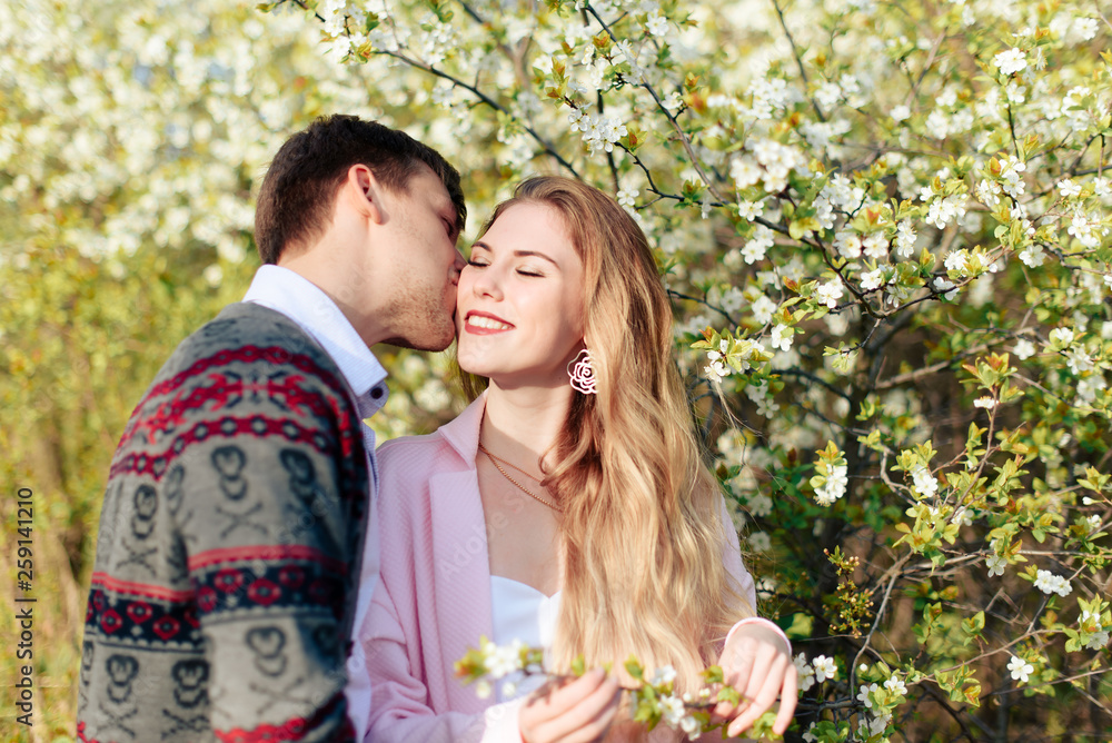 a young couple in love cuddles against the background of blooming spring cherry orchards 1 a young couple in love cuddles against the background of blooming spring cherry orchards 1