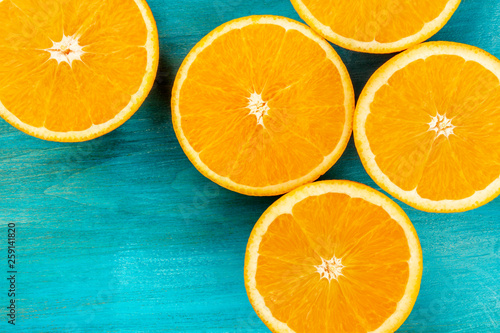 Orange halves, shot from the top on a vibrant blue background with copy space