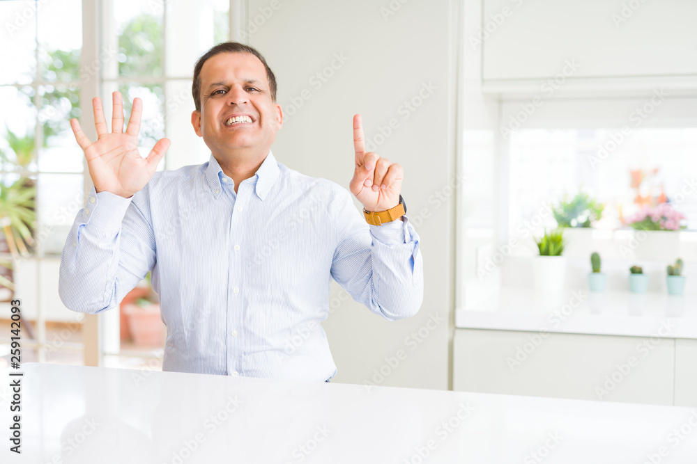 Middle age man sitting at home showing and pointing up with fingers number six while smiling confident and happy. Middle age man sitting at home showing and pointing up with fingers number six while smiling confident and happy.