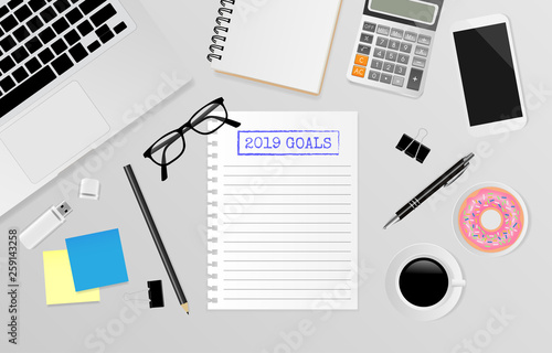 2019 goals text on white note paper with office supplies on gray background