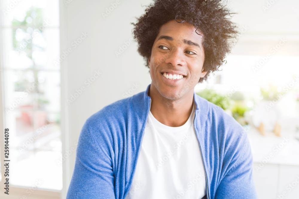 African American man at home smiling looking side and staring away thinking.