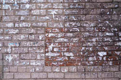 Old brick wall of the house with the torn-off ads. photo