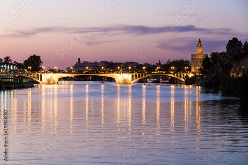 Sevilla, Spain. Views of the Guadalquivir river, with the Torre del Oro (Tower of Gold) and the Puente de San Telmo bridge at sunset