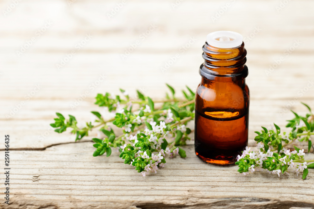 thyme essential oil and thyme flowers on the wooden board thyme essential oil and thyme flowers on the wooden board