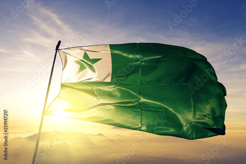Esperanto flag waving on the top sunrise mist fog photo