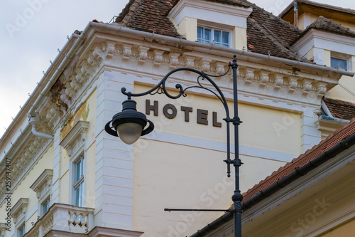 Bild auf Leinwand Generic hotel sign framed by an artistically curved street lamp, with renovated old buildings in the background