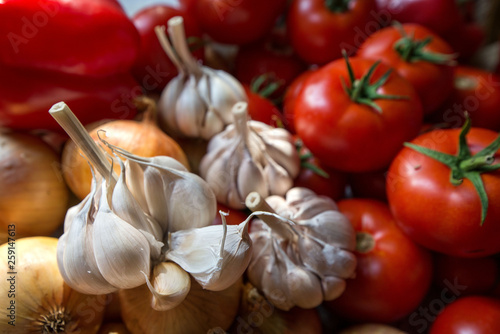 Fototapeta Naklejka Na Ścianę i Meble -  Ripe, fresh, harvested vegetables on table. Onions, tomatoes, garlic on kitchen table prepared to make a delicious vegetarian meal or for canning veggies for winter in jars. Concept of healthy eating