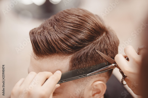 Photography Close-up, master hairdresser does hairstyle with scissors comb