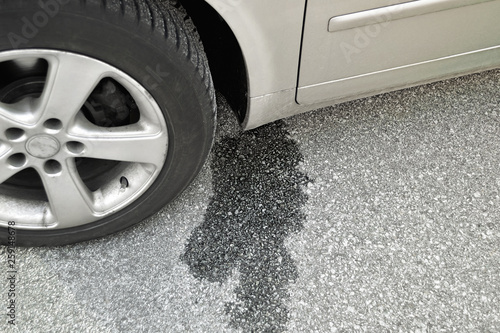 Spilled engine oil or gasoline near the car wheels. Car breakdown