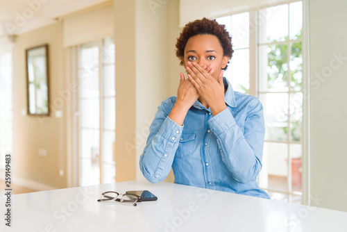 Young beautiful african american woman shocked covering mouth with hands for mistake. Secret concept.