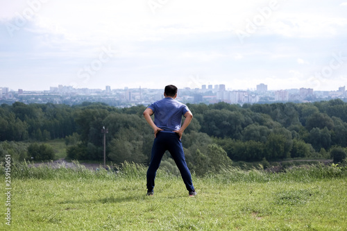 Korean man stretches against the background of the city. Healthy lifestyle. Adult man practicing yoga in nature.
