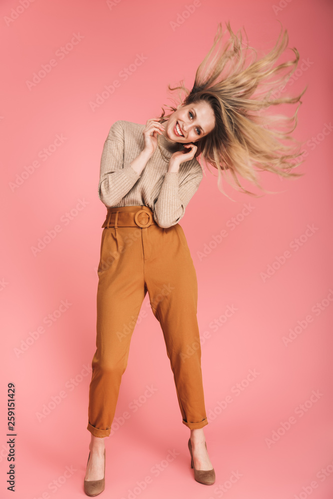 Full length portrait of stylish woman smiling and having fun isolated over pink background