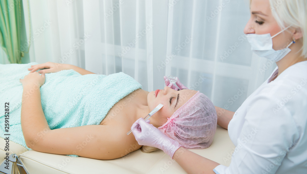 Fototapeta premium spa, cosmetologist applying cream mask on face