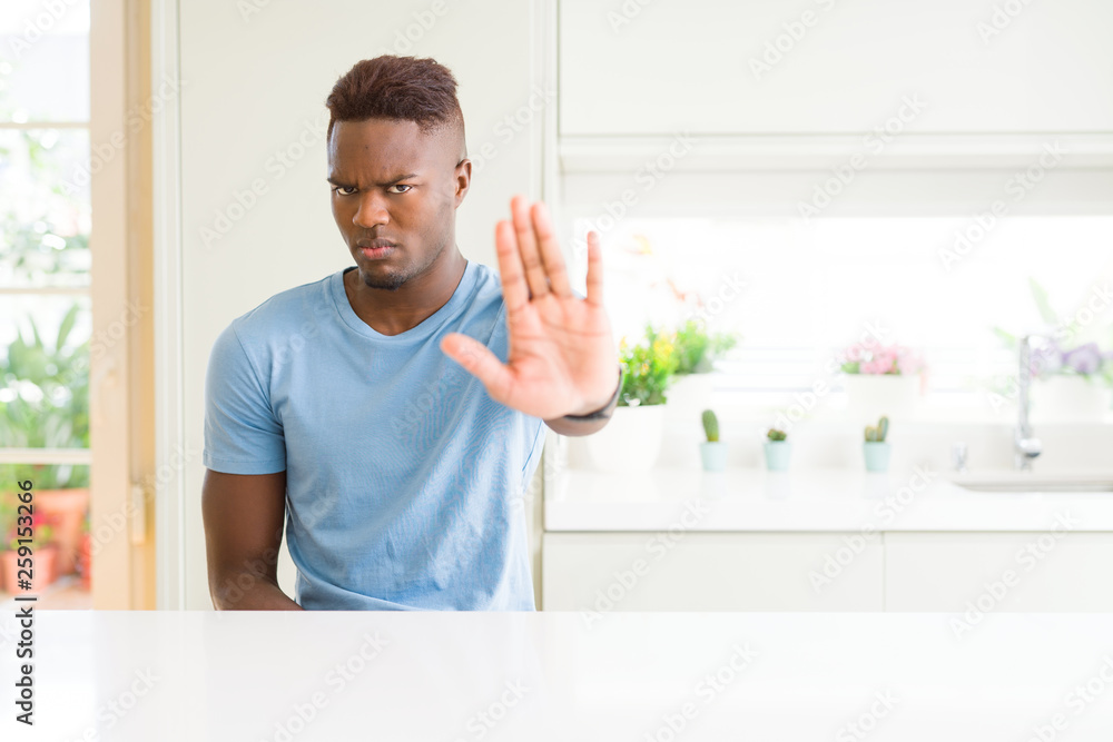 Handsome african american man wearing casual t-shirt at home doing stop sing with palm of the hand. Warning expression with negative and serious gesture on the face.