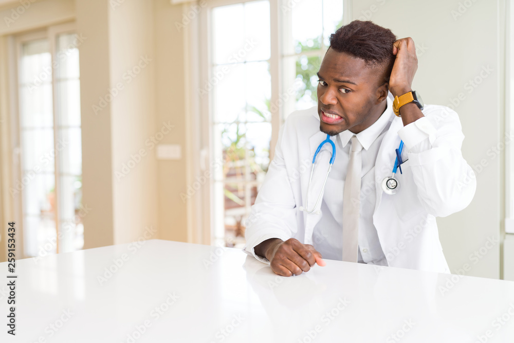 African american doctor man at the clinic confuse and wonder about question. Uncertain with doubt, thinking with hand on head. Pensive concept. African american doctor man at the clinic confuse and wonder about question. Uncertain with doubt, thinking with hand on head. Pensive concept.