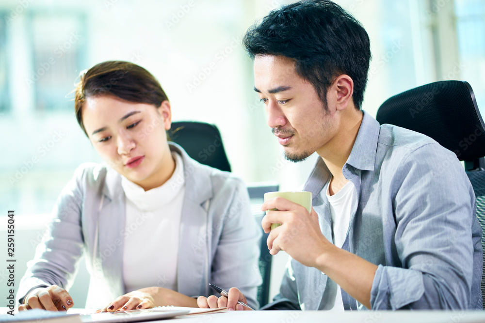 two asian business people working together in office two asian business people working together in office