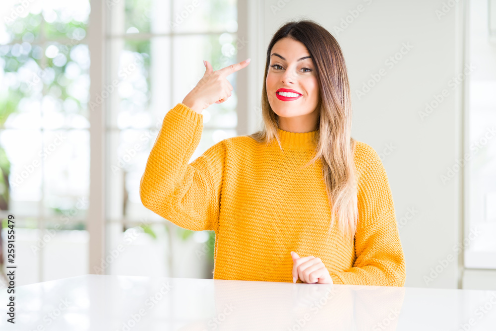 Young beautiful woman wearing winter sweater at home Smiling pointing to head with one finger, great idea or thought, good memory Young beautiful woman wearing winter sweater at home Smiling pointing to head with one finger, great idea or thought, good memory