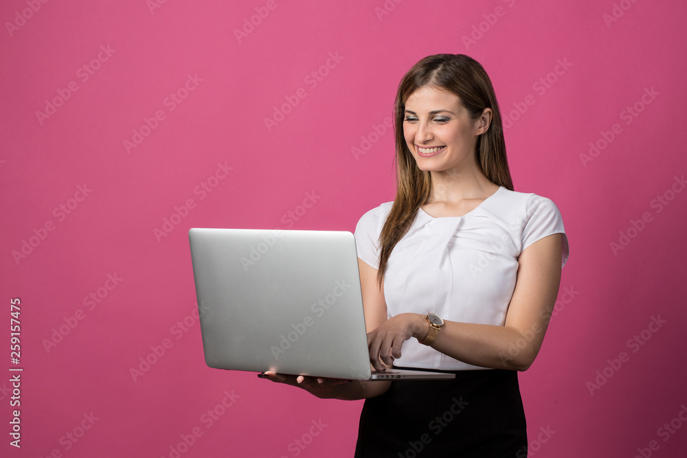 Naklejka premium young blond woman using laptop isolated on pink background