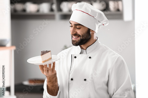 Male confectioner with piece of tasty cake in kitchen photo