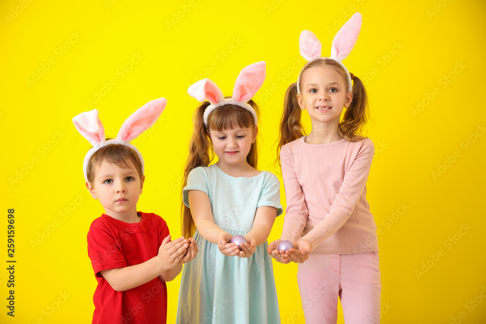 Cute little children with Easter eggs and bunny ears on color background Cute little children with Easter eggs and bunny ears on color background
