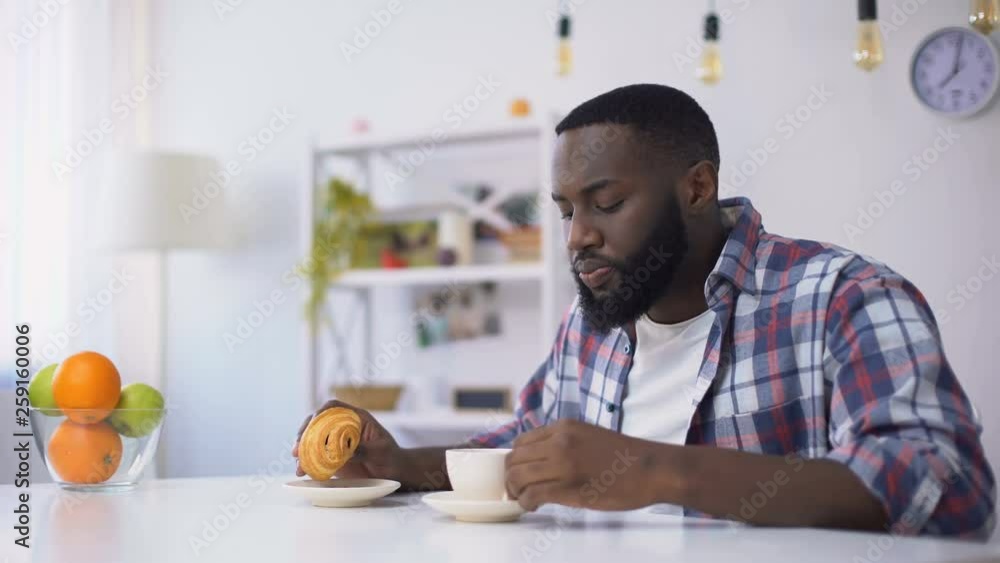 Black man eating croissant with coffee, feeling tooth ache from sweet food Black man eating croissant with coffee, feeling tooth ache from sweet food